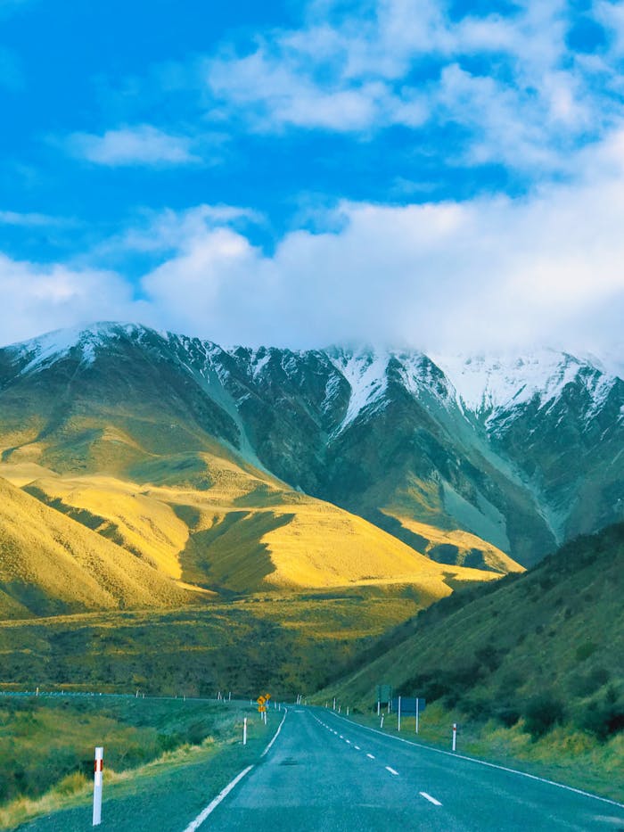 Picturesque view of snow-capped mountains and open road in Canterbury, New Zealand.